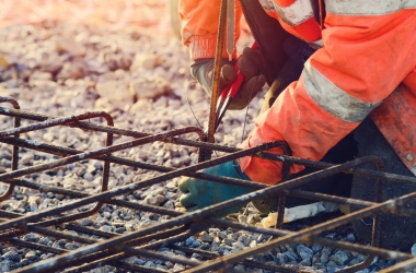 Builder's hands fixing steel reinforcement bars at construction site
