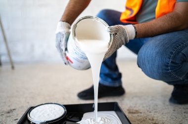 construction worker pouring paint indoors